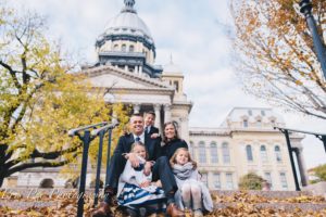 The executive director of Civil Servant Ministries Curt Fleck is sitting with his family in front of the State Capitol where he holds weekly bible studies with lawmakers.